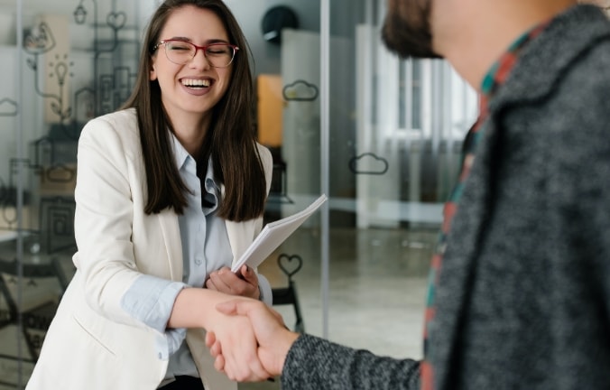 woman with glasses shaking a man's hand and smiling