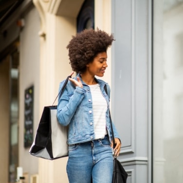 Woman walking and smiling with shopping bag